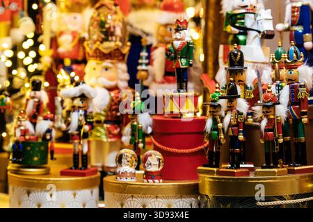 A colourful display of traditional wooden nutcracker figures arranged on festive boxes, surrounded by warm holiday lights and Christmas decorations Stock Photo