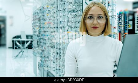 Professional young female optician posing with a smile in a brightly lit store Stock Photo