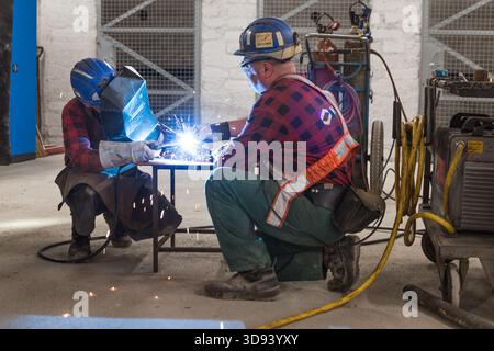 LUBIN, POLAND - OCTOBER 7, 2019 : Blue color workers welds the pipe in the workshop in copper mine that belongs to KGHM Polska Miedz. Stock Photo