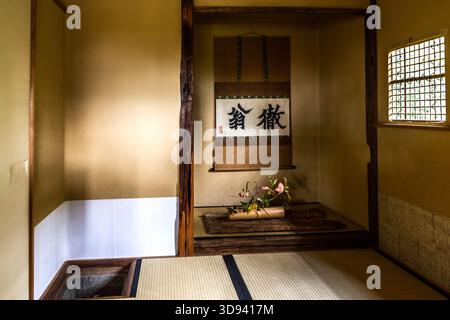 The tokonoma alcove of a traditional tea house (����) on the grounds of the Enoura Observatory (��֮�֜y����) in Odawara, Kanagawa Prefecture, Japan. Hanging in the tokonoma is a calligraphy scroll bearing the characters ����, the pseudonym of the Zen monk Tetsu�� Gik�� (1295�C1369); beneath it is an ikebana arrangement. Tatami flooring and a sunken hearth (¯) are typical features of a formal tea room Stock Photo