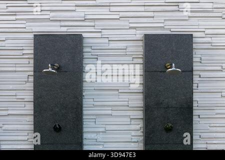 rain shower with tap on black marble and white slate wall background. Stock Photo