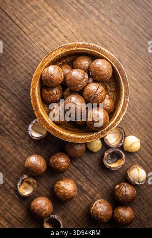 Tasty macadamia nuts in bowl on a wooden table. Top view. Stock Photo