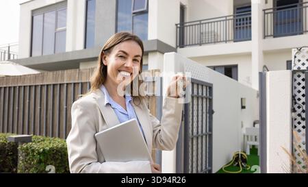 Smiling real estate agent with house keys posing outdoors Stock Photo