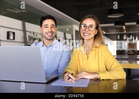 Two cheerful young coworkers working together at laptop Stock Photo