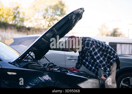 Automobile checkup conducted, Car battery inspected in neighborhood Stock Photo