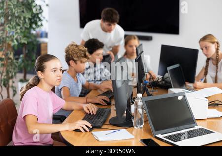 Focused girl studying with classmates in school classroom Stock Photo
