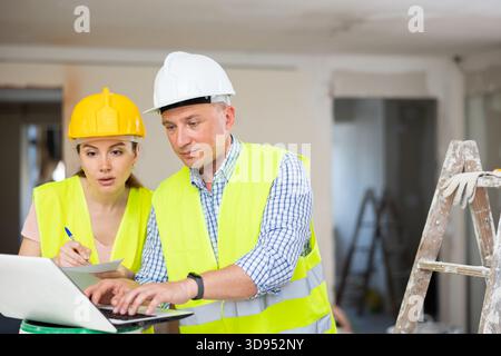 Woman architect and man engineer using laptop in construction site Stock Photo