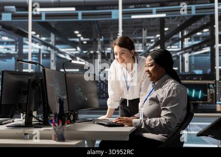 Admins in data center smiling while checking infrastructure health report showing stable performance indicators. Engineer pleased in server hub after successfully completing scheduled diagnostics Stock Photo