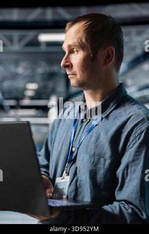 Server farm employee conducting security audits to protect against cyber threats. Data center engineer analyzing system performance, deploying cybersecurity measures to secure assets Stock Photo