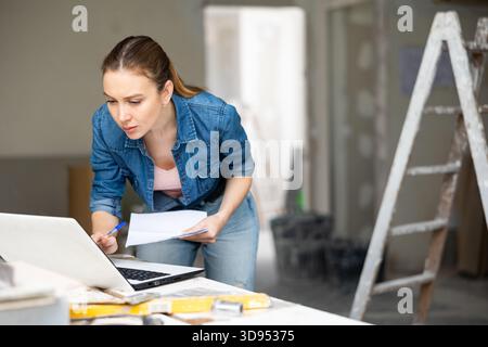 Woman with laptop at house being renovated Stock Photo