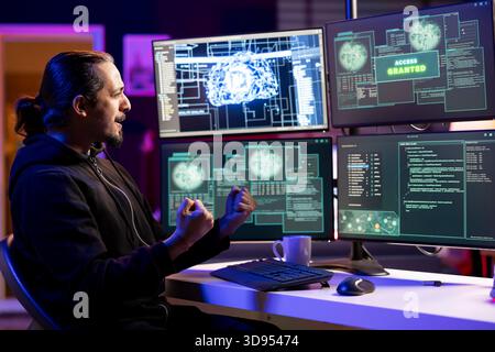 Cheerful rogue programmer delighted after getting access granted message after using undetectable malware. Hacker doing victory hand gesture after breaching firewall security using data mining script Stock Photo