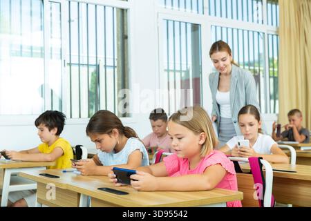 Pupils using mobile phones during lesson in school Stock Photo