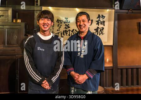 Two owners (father and son) of the Amazake Chaya (�ʾƲ���) in Hakone, Kanagawa Prefecture, Japan, wearing traditional work attire. In the background is a calligraphy scroll bearing the character for Hakone (���). The Amazake Chaya is one of the oldest tea houses still in operation on the historic Tokaido Road Stock Photo