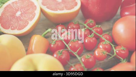 Showing cherry tomato cluster resting on kitchen cutting board, halved grapefruit, pepper, peaches Stock Photo