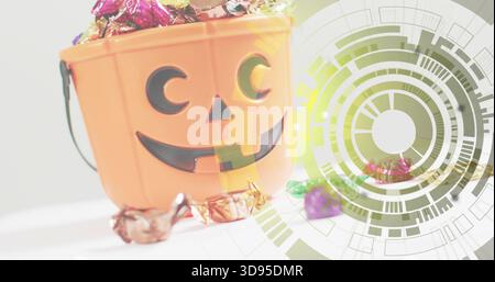 Overflowing orange jack-o'-lantern bucket spilling foil candies on white table, with green overlay Stock Photo