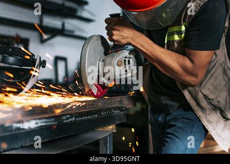 Metalworking professional using an angle grinder in the workshop. Man using a grinder in a workshop Stock Photo