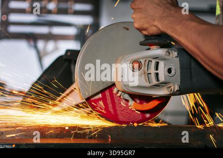 Close-up of an angle grinder cutting metal on a workbench. Close-up of a man using a grinder on an anvil Stock Photo
