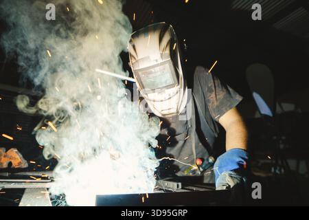 Close-up of a deaf man using a welding torch in the workshop. Close up of a professional welder working at the workbench Stock Photo
