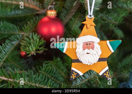 Santa Clause star shaped ornament hanging in a Christmas tree. Stock Photo