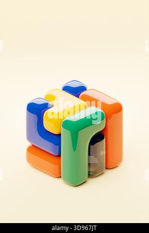 A stylized 3D cube featuring a palette of multiple colors, set against a lush red background, illustrating a digital abstract form Stock Photo