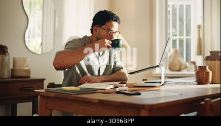 Man, coffee and reading with laptop at house for research, copywriting and editor feedback. Person, remote work and beverage for proofreading on pc Stock Photo