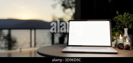 White screen laptop with aroma candles and acorns on round wooden table at the terrace or rooftop. Study or Working, 3D Rendering, 3D Illustration. Stock Photo