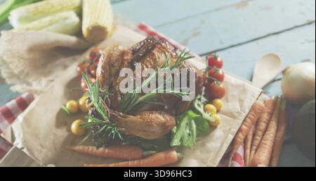 Displaying roasted chicken sitting on parchment on cutting board in rustic kitchen, with rosemary Stock Photo