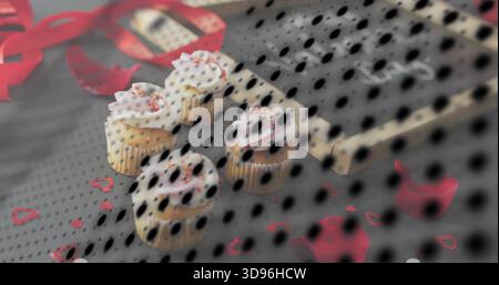 Showing four frosted cupcakes resting on party table with red ribbon, heart confetti and black mesh Stock Photo