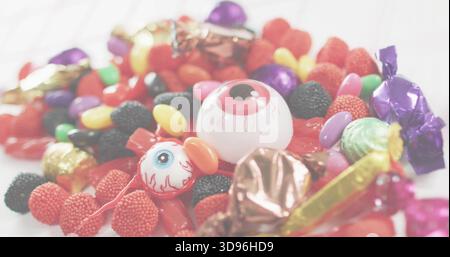 Displaying candy mix on white tabletop, with large white eyeball and small eyeball pop, foil wraps Stock Photo
