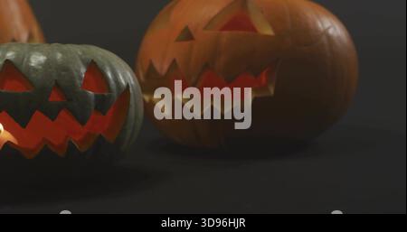 Glowing pair of carved jack-o'-lantern pumpkins casting warm light, showing internal glow in studio Stock Photo