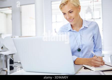 Happy, laptop and business woman with notebook for administration, planning and task schedule. Office, corporate and person on computer and writing Stock Photo