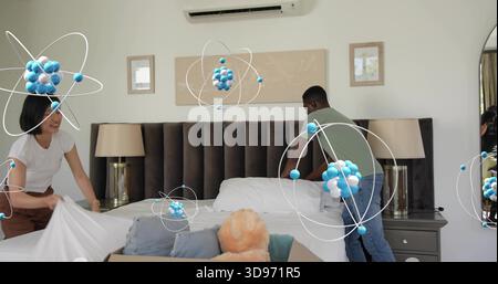 Making man green-shirt woman white-top arranging bed in bedroom, with teddy and blue overlays Stock Photo