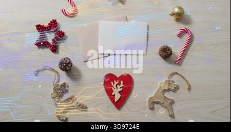Showing red heart with white reindeer centred on wood table, envelopes, candy cane, circuit overlay Stock Photo