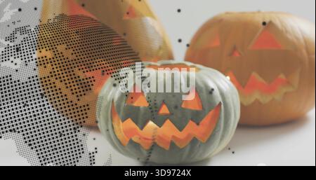 Showing green-gray carved pumpkin glowing inside among two orange pumpkins on white table, halftone Stock Photo