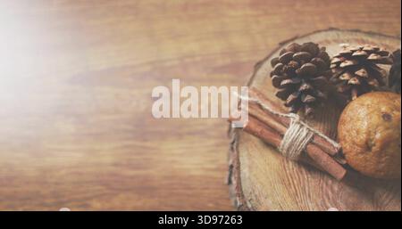 Displaying three pine cones, cinnamon sticks tied with twine, baked item on round slab, copy space Stock Photo
