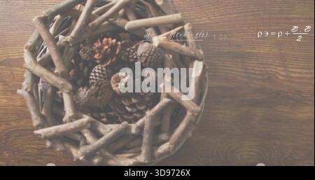 Displaying woven twig basket left on wood table, holding pine cones, showing white formulas overlay Stock Photo