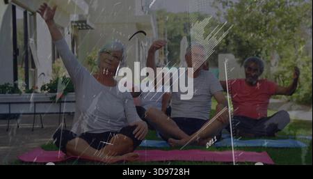 Stretching four senior adults sitting cross legged on grass lawn, in activewear on exercise mats Stock Photo