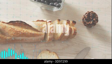 Showing sliced baguette lying on wooden table, with berry bowl, pinecone, knife, turquoise overlay Stock Photo
