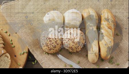 Displaying breads and rolls on rustic burlap table with scattered pepita seeds and metal knife Stock Photo