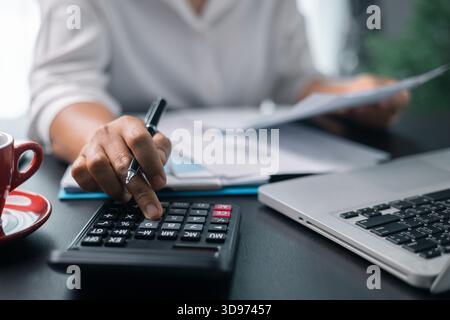 Businesswoman working on desk office with using a calculator to calculate the numbers, finance accounting concept. Woman accountant use calculator and Stock Photo