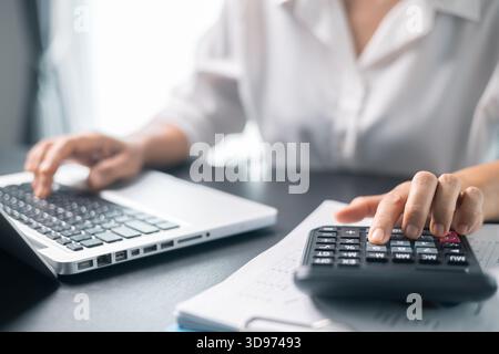 Businesswoman working on desk office with using a calculator to calculate the numbers, finance accounting concept. Woman accountant use calculator and Stock Photo