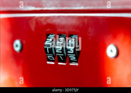 Detailed view of a three-digit numerical combination mechanism on a brightly colored red object, emphasizing the code "123" for security, access contr Stock Photo