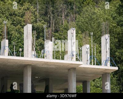 Construction of a monolithic-frame building with a mountain covered in dense forest rising behind it Stock Photo