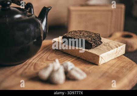 Vintage Chinese teapot crafted from dark clay brewing fragrant tea on a natural cherry-wood board, with rising steam and soft warm light creating Stock Photo
