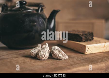 A rustic Chinese clay teapot preparing loose-leaf tea on a polished cherry-wood board, surrounded by delicate details of an authentic tea ritual Stock Photo