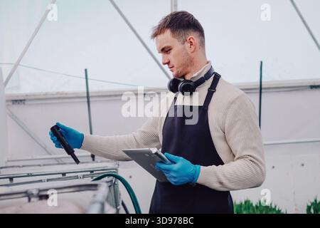 Physiologist analyzing tulip growth conditions carefully, Agricultural scientist conducting detailed experiments on tulips using specialized equipment Stock Photo