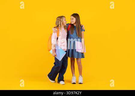 Two preteen girls standing with notebooks and smiling in bright studio background Stock Photo