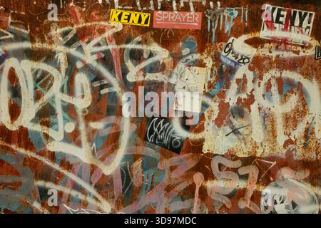 Asoke, BangkokThailand- December 03 2025: A chaotic layer of street graffiti covering a rusted metal wall in Bangkok, reflecting urban decay and visu Stock Photo