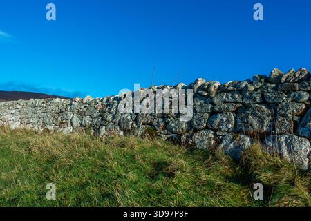 A dry stone dyke, or wall, in front of a blue sky in Scotland Stock Photo