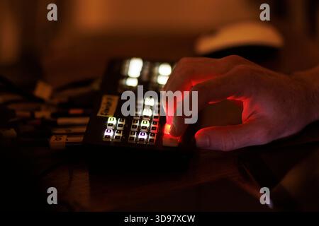 Close up of a hand operating a control panel with glowing buttons during a live event. Stock Photo